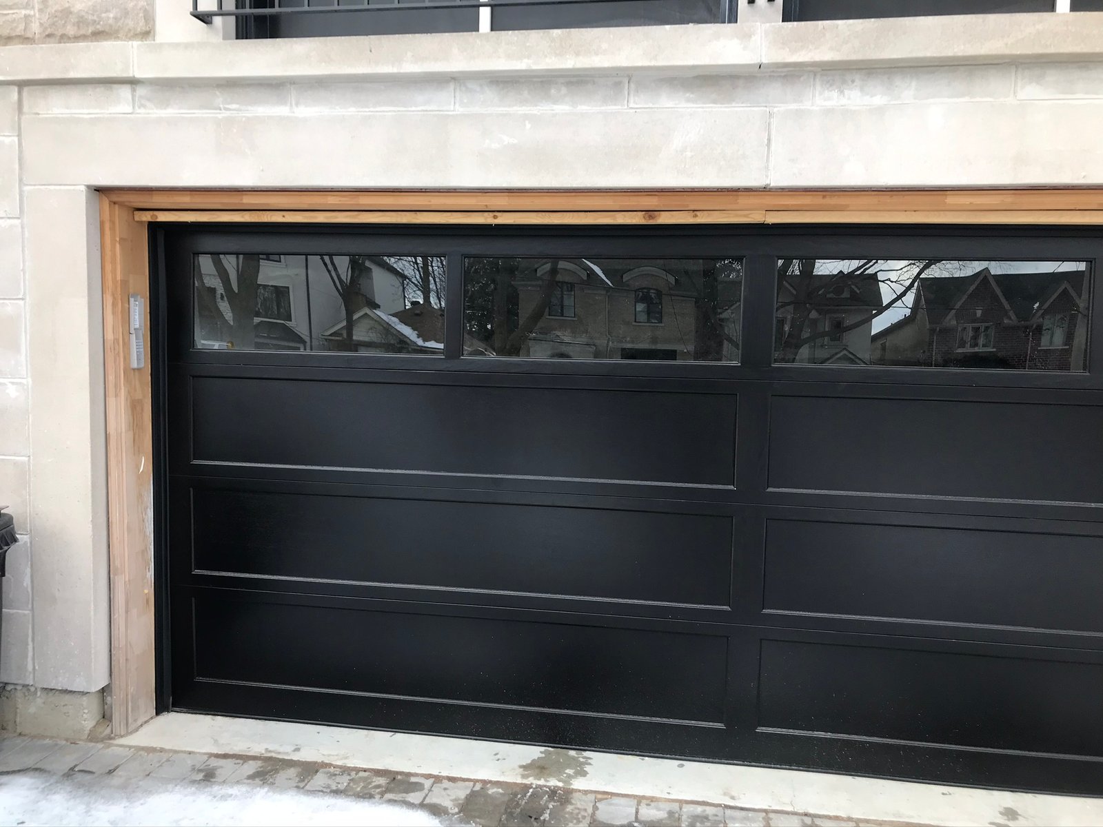 Black garage door with cedar header trim