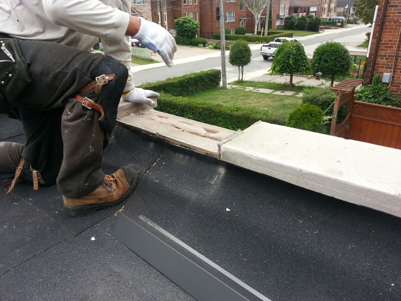 Roofer inspecting and sealing a chimney crown